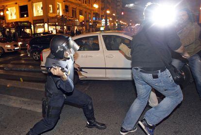 Un polic&iacute;a antidisturbios carga contra un grupo de personas en el entorno del Instituto Llu&iacute;s Vives, en Valencia.