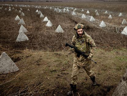 Ukrainian military engineer with the call sign "Lizard" walks near fortifications, including "dragon's teeth" and barbed wire, that he helped to build in a field near the front line outside Kupiansk, amid Russia’s attack on Ukraine, December 28, 2023.  REUTERS/Thomas Peter     TPX IMAGES OF THE DAY