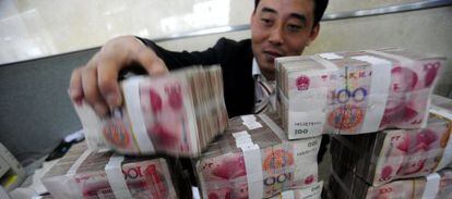 Un empleado de un banco en Hefei (centro de China) manipula paquetes de billetes de yuanes.