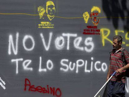 Un hombre pasa al lado de un cartel contra la votaci&oacute;n de este domingo.