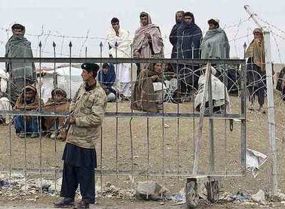 Un soldado vigila la frontera entre Pakistán y Afganistán mientras un grupo de afganos espera para cruzar.
