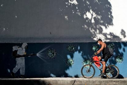Un hombre en bicicleta pasa ante un mural sobre el coronavirus en Río de Janeiro el pasado 8 de julio.