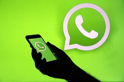 Foto ilustración del logo de WhatsApp en la pantalla de un iPhone enfrente de una televisión.