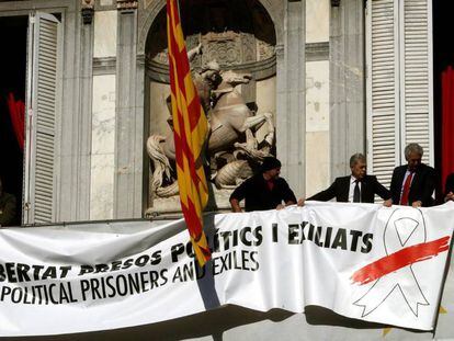 Trabajadores de la Generalitat colocan una pancarta con un lazo blanco encima de la que había antes.