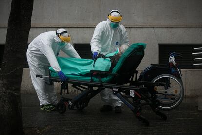 Personal sanitario traslada de su vivienda a una anciana contagiada por coronavirus, en Barcelona.