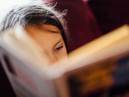 Una niña lee con atención un libro.