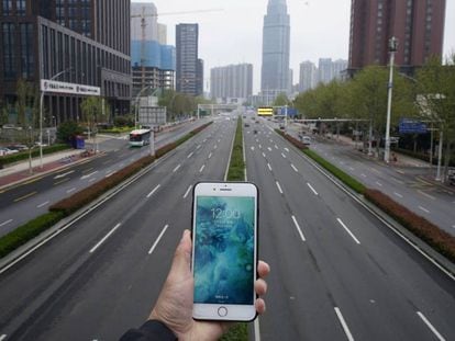Una persona sostene un teléfono móvil frente a una carretera casi vacía en Wuhan, China, el pasado 31 de marzo.