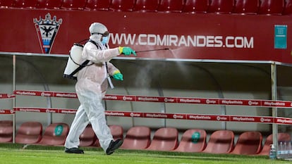 Un operario desinfecta los banquillos del estadio Municipal de Anduva.