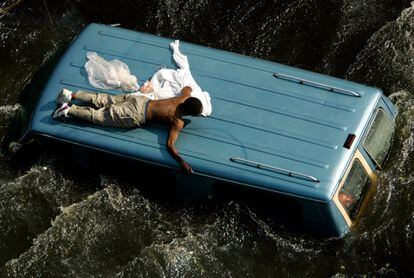 Un hombre espera sobre el techo de una furgoneta a ser rescatado por los guarda costas de EE UU, el 4 de septiembre de 2005, en Nueva Orleans.