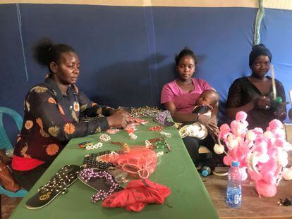 A la izquierda, Emily Wairimu Maina, voluntaria de salud comunitaria, enseña a Zahara Akinyiy a otra joven madre a diseñar abalorios para que después los puedan vender.