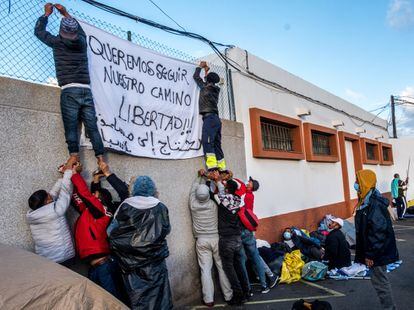 Varios migrantes expulsados por Cruz Roja cuelgan una pancarta frente al local de la entidad para exigir una vía alternativa al desentendimiento.