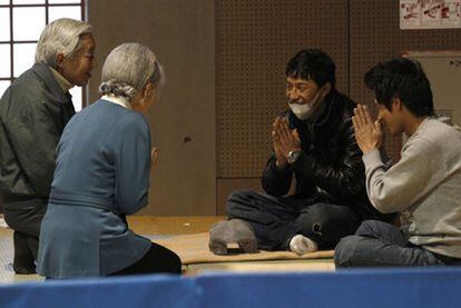 Dos evacuados saludan a los emperadores durante su visita a un centro para desplazados en Tokio.