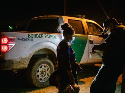 Un oficial de la patrulla fronteriza procesa a una mujer migrante después de cruzar el Río Grande hacia Texas (EE UU).