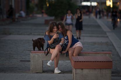 Dos adolescentes miran un teléfono tras tomar una foto en una calle de Tesalónica (Grecia).