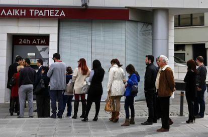 Clientes hacen cola ante un cajero del Banco Popular de Chipre.