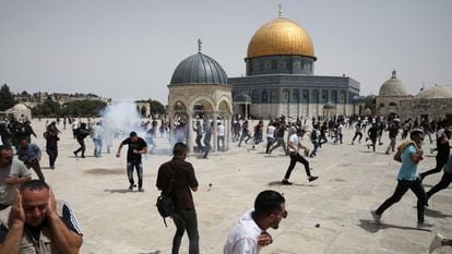 Decenas de palestinos corren tras el lanzamiento de granadas aturdidoras por agentes israelíes, este viernes en la Explanada de las Mezquitas de Jerusalén. 