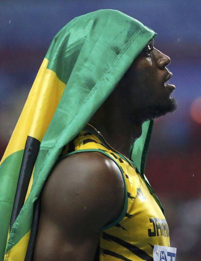 Bolt cubre su cabeza con una bandera de Jamaica.