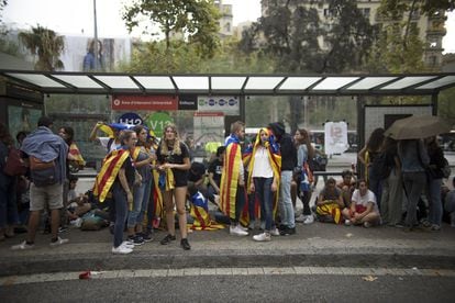 Varios estudiantes se protegen de la lluvia en una parada de bus durante la protesta de estudiantes ante la sede de la Universidad de Barcelona a favor de la celebración del referéndum del 1 de octubre.