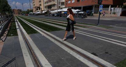 Una mujer cruza por las vías del metro de Granada, en el barrio del Zaidín.
