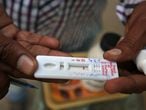 Un trabajador sanitario muestra un test rápido de malaria después de haber tomado una muestra de sangre a un paciente durante una campaña de prevención de la enfermedad en Ahmedabad, India.