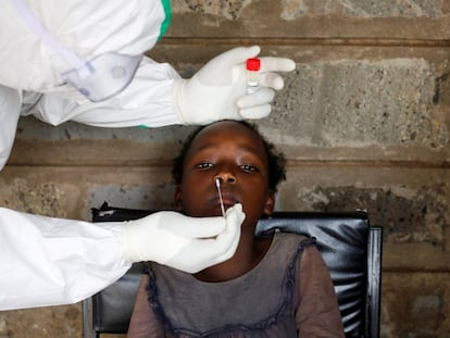 Un sanitario realiza una PCR a una niña durante una prueba masiva en un barrio marginal de Kibera en Nairobi (Kenia).