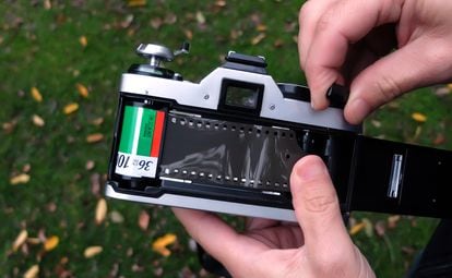 Un aficionado coloca un carrete de película fotográfica en una cámara analógica.