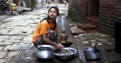 Una niña nepalí friega sus platos en Katmandú (Nepal).