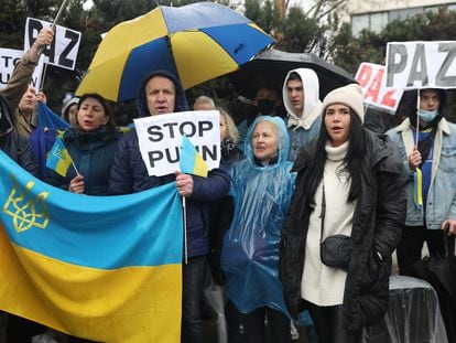 Un grupo de personas con carteles y una bandera de Ucrania participa en una nueva concentración ante la embajada rusa de Madrid tras los ataques en Ucrania, este viernes.