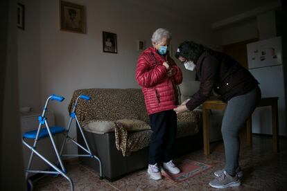 Una cuidadora atiende a una mujer mayor en su casa en Manzanares El Real (Madrid).