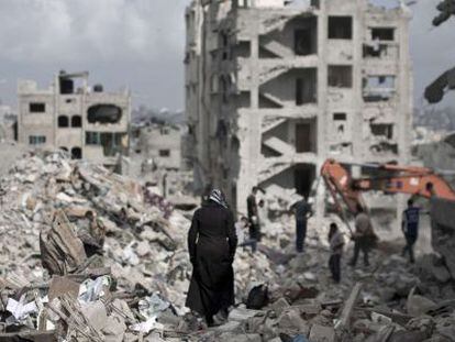 Una mujer palestina camina entre los escombros de las casas en Gaza.