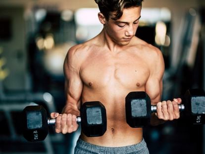 Un adolescente ejercita sus músculos en el gimnasio.