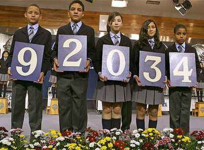 Los niños del colegio de San Ildefonso muestran el primer premio del sorteo de lotería de <i>El Niño</i>.
