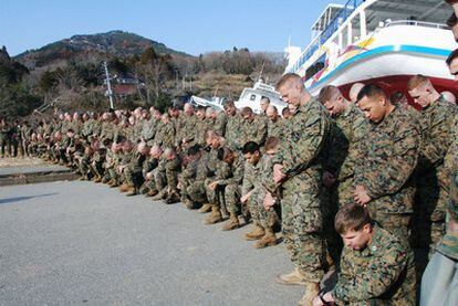 Marines de EE UU guardan un minuto de silencio antes de comenzar la búsqueda de cadáveres en la aldea de Kesennumaoshima.