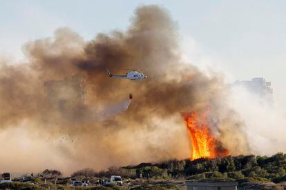  Un helicóptero trabaja en las labores de extinción del incendio forestal declarado a primera hora de la tarde de este lunes en El Saler, en València.