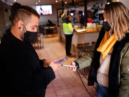Un camarero solicita el pasaporte covid a un cliente en un restaurante de Terrassa.