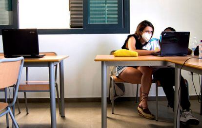 Una voluntaria enseña a un alumno a utilizar un ordenador en el colegio Corpus Christi de Sevilla.