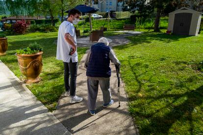 Un trabajador de una residencia en Thises, en el este de Francia, acompaña a una anciana en su paseo por el jardín del centro