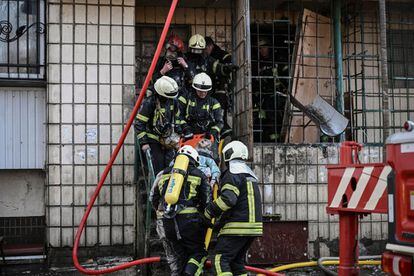 Los bomberos trasladan el cuerpo de una mujer muerta por los bombardeos en un edificio de Kiev, el martes.