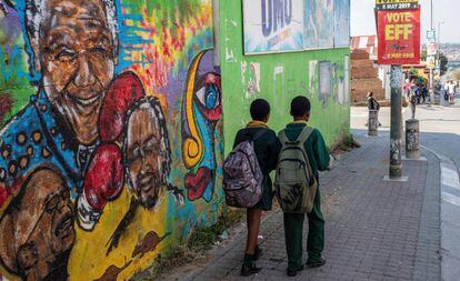 Dos estudiantes caminan frente a un mural de Nelson Mandela, este martes en Johannesburgo.