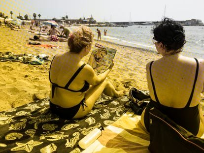 Una mujer ojea la revista '¡Hola!' en la playa de Barcelona.