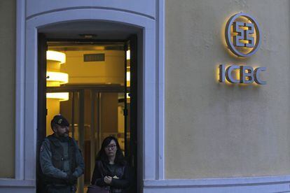 Una mujer abandona la sede del ICBC en España bajo la mirada de un agente de la Guardia Civil.