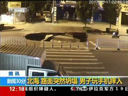 Un motorista, a punto de caer en un socavón, en China.