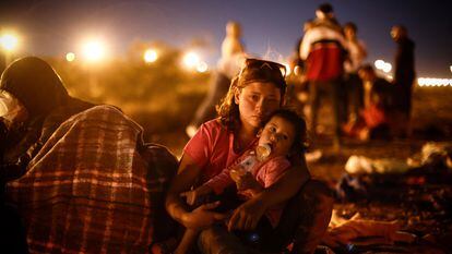 Una migrante de origen venezolano con su bebé  esperan para intentar cruzar.