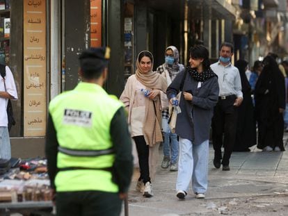 Varias mujeres, una de ellas sin velo, caminan cerca de un policía en Teherán el 16 de julio de 2023.