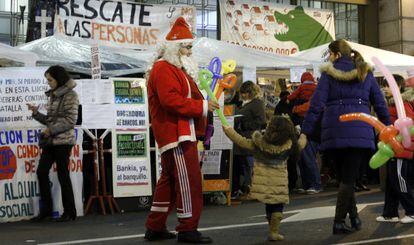 Papá Noel reparte globos frente a los acampados de Bankia.