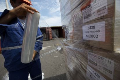 Un trabajador envuelve cajas en plástico antes de cargarlas en un contenedor de envío en el Puerto de Veracruz.