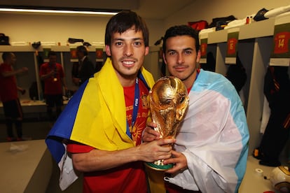 Silva, con la bandera de Las Palmas, y Pedro con la de Tenerife, sostienen la Copa del Mundo conseguida por España en Sudáfrica 2010.