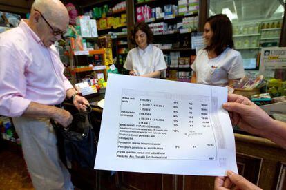 Una persona muestra un folio con los criterios para aplicar el copago en una farmacia de Barcelona el pasado mes de julio.
