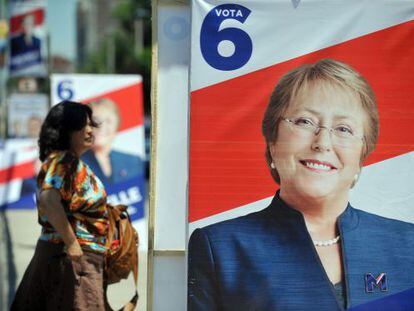 Una mujer camina al lado de la propaganda pol&iacute;tica de Bachelet. 