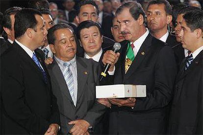 El presidente mexicano, Vicente Fox, entrega una copia de su informe de gobierno antes de abandonar la sede del Legislativo.